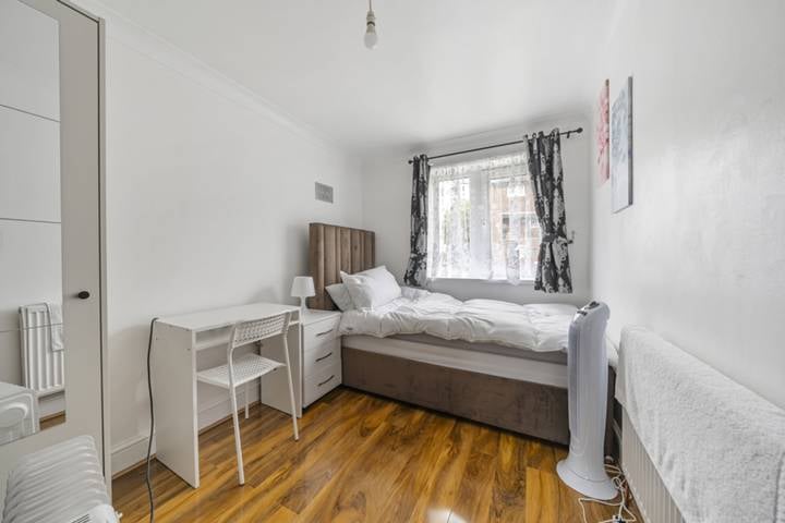 Single bed by window, wooden floor, small desk with chair, and wardrobe