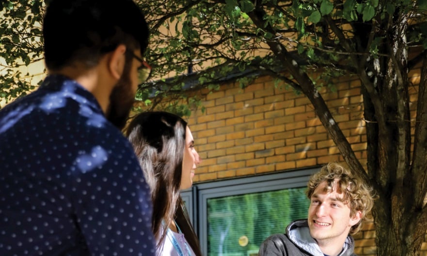 Three students chatting by a university building