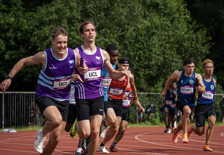 Two UCL athletes hand off the baton in the men's 4x100m relay.