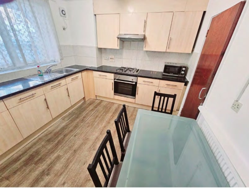 kitchen with table, washing machine, two fridges and a microwave
