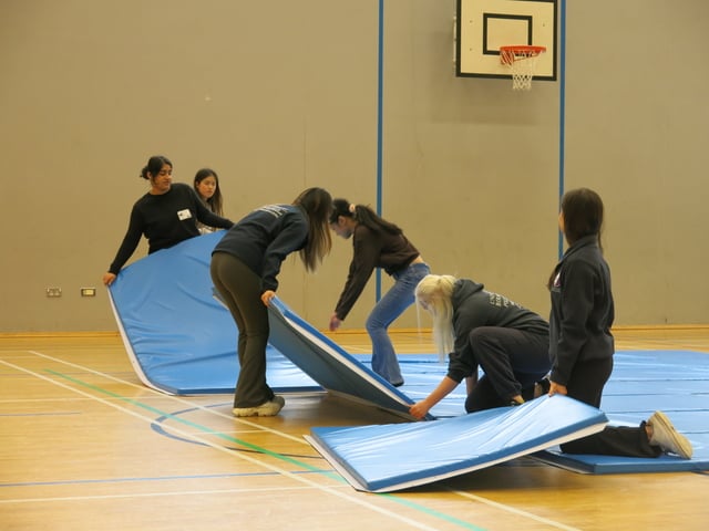 students and volunteers arranging floor mats in the gym