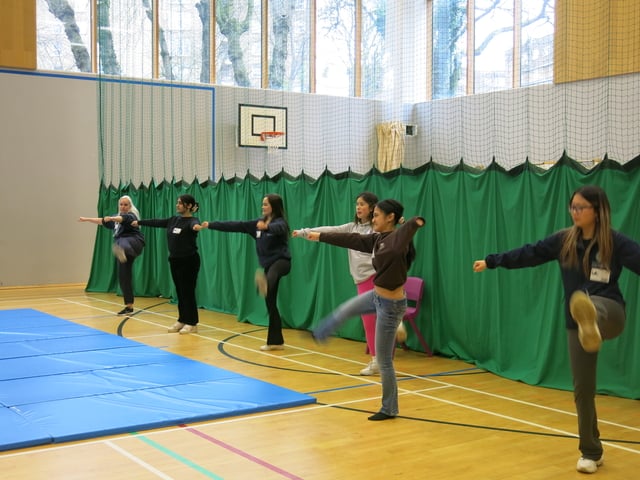 students and volunteers doing leg exercises in the gym