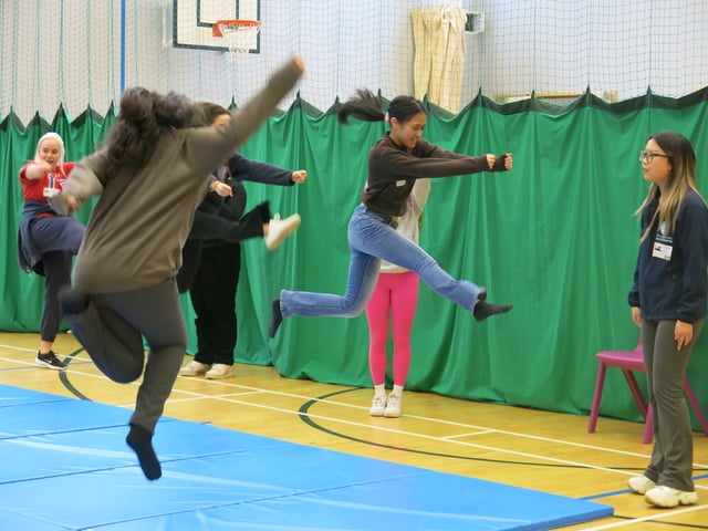 students and volunteers doing jumps in the gym