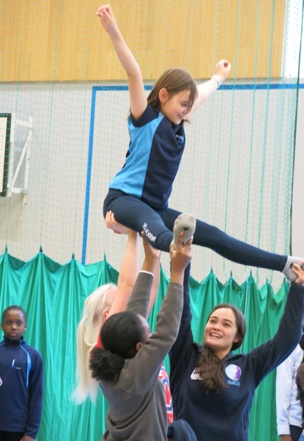 students and volunteers doing a gymnastic's lift