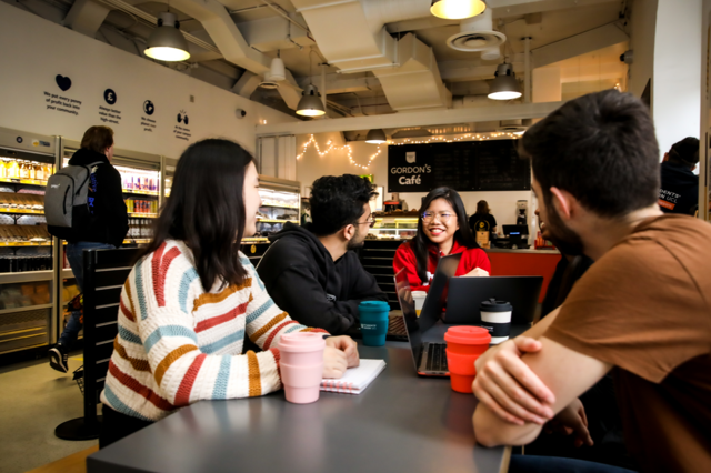 Group of students talking and drinking coffee looking happy in Gordons Cafe