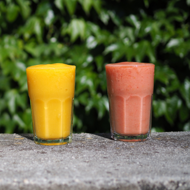 Two smoothies - one orange, one pink served in glasses