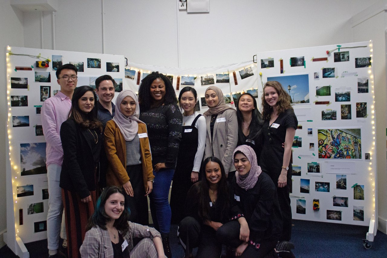 Group of student volunteers standing in front of photo exhibition