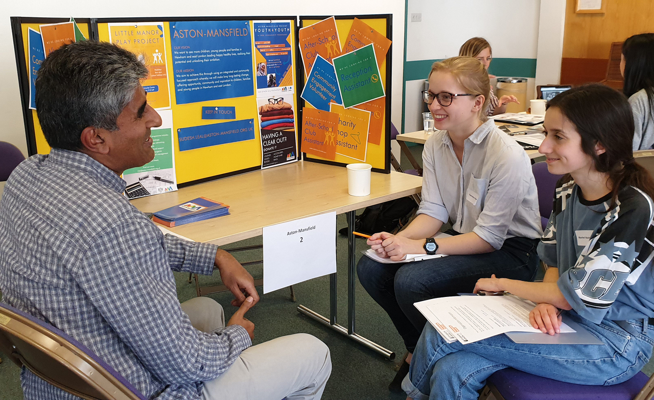 Two students speaking with someone from a community organisation