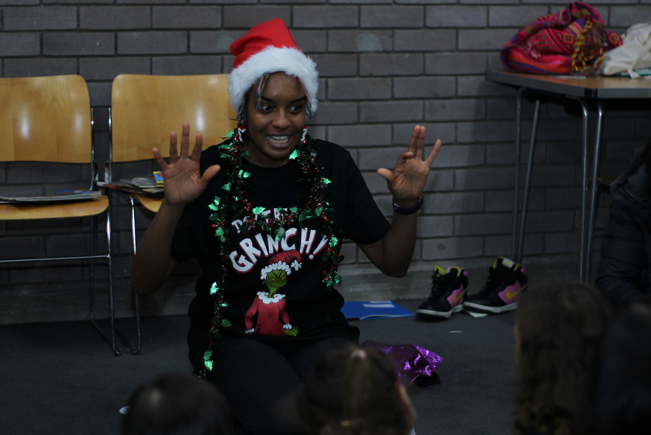 student volunteer with santa hat and grinch tee shirt